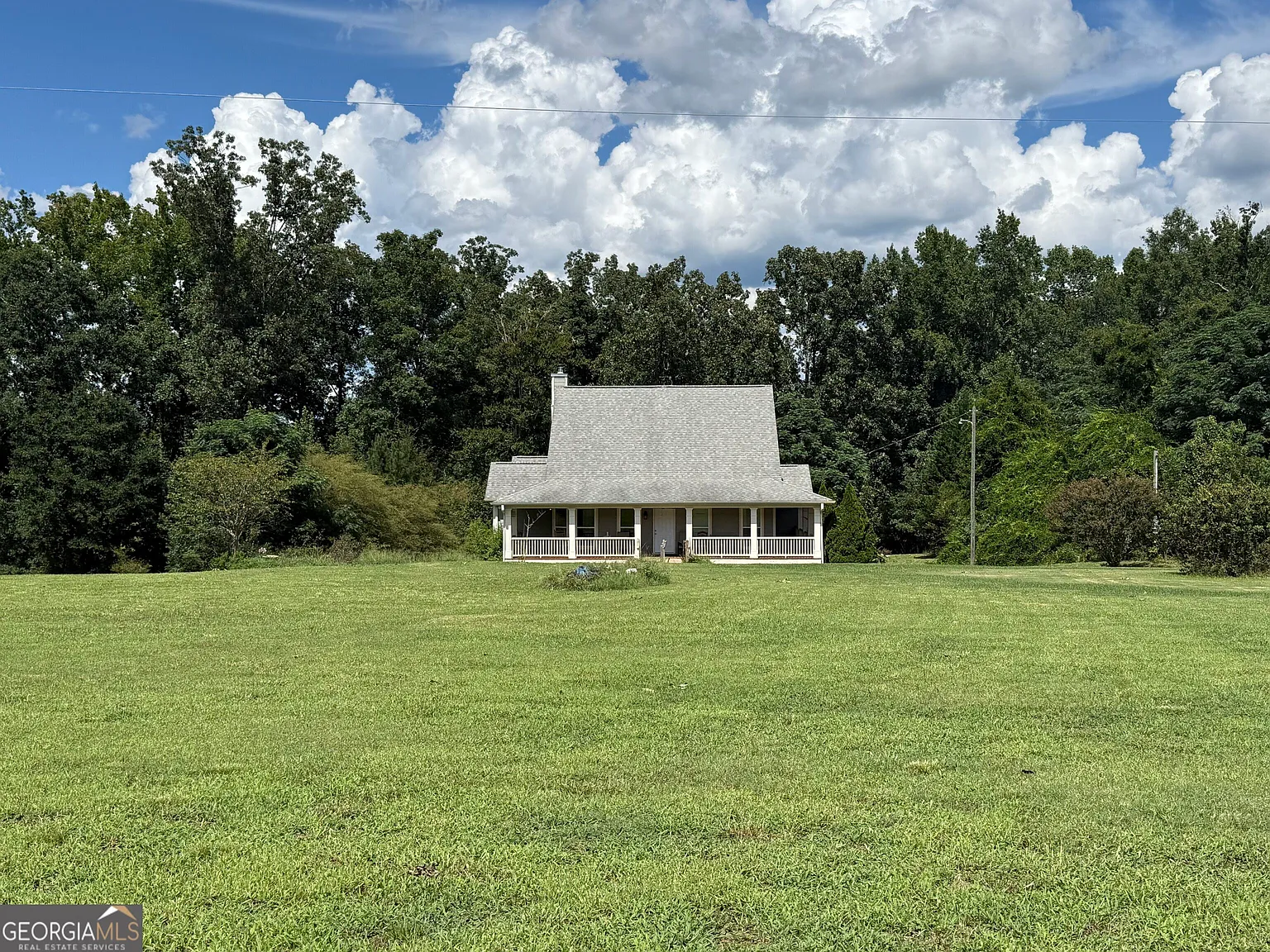 A Wraparound Porch With Grazing Cattle Next Door