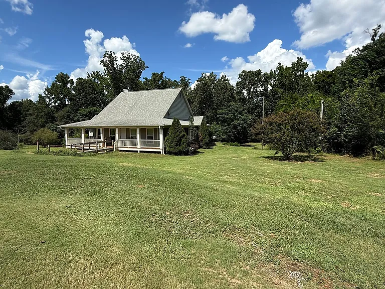A Wraparound Porch With Grazing Cattle Next Door